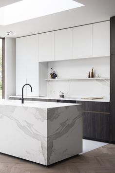 a modern kitchen with marble counter tops and white cabinets, along with wooden flooring