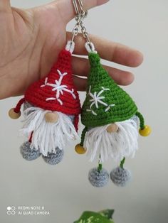 two crocheted gnome keychains are being held by a person's hand