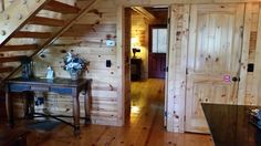 a room with wooden walls and stairs next to a table in front of a door