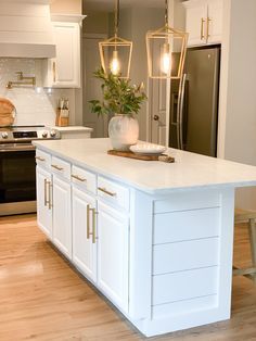 a kitchen with white cabinets and an island that has gold pulls on the doors,