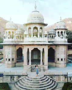 a woman standing in front of a white building with many arches and domes on it