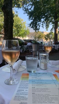 two glasses of wine sitting on top of a table next to a menu and napkin