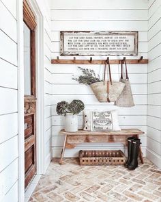 an entry way with white walls and wooden shelves filled with pots, vases and plants