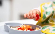 a small child is eating fruit from a bowl