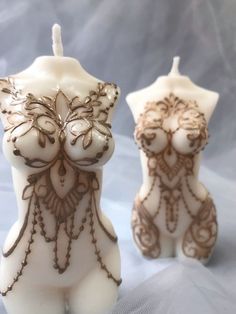 two white candles with brown designs on them