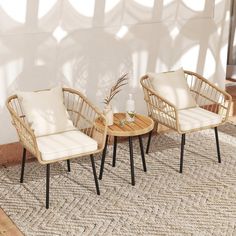 two wicker chairs sitting on top of a rug next to a table with a plant