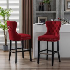 two red chairs sitting next to each other in front of a sink and counter top