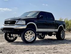 a black truck parked on top of a dirt field