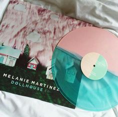 a pink and blue vinyl record sitting on top of a bed