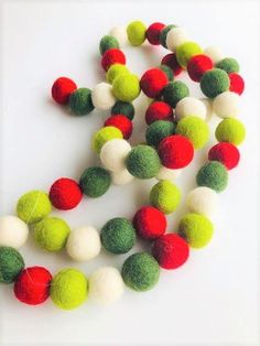 multicolored felt ball garland on white background with red, green and white balls