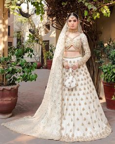 a woman in a white lehenga with gold embellishment on her chest