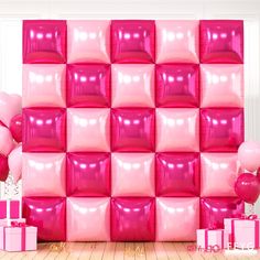 pink balloons and gift boxes in front of a wall made out of shiny plastic cubes