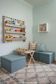 Bright and inviting children's playroom featuring a wall-mounted shelf filled with colorful toys, a low wooden table with building blocks, and cozy seating with patterned cushions. The light blue walls create a cheerful atmosphere, perfect for play and creativity. Half Playroom Half Bedroom, Toddler Playroom Ideas For Boys, Living Room And Playroom Combo, Cool Playroom Ideas, Cool Playroom