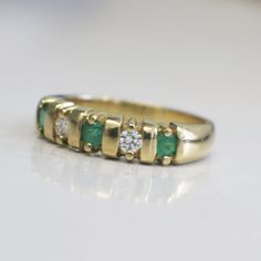 This stunning 18K yellow gold ring features two very white round brilliant cut diamonds and three bright green round emeralds. This ring is perfect for an anniversary band, wedding band, or stackable ring. The contrast of the colors makes sure this ring stands out! Metal: 18K Yellow Gold Diamonds: .20 CTW, VS1-VS2, E-F Color Emeralds: 3 MM Each Band Width: 3.44 - 5.00 MM Size: 7 For a greater selection of jewelry please visit our website at www.BlackMarketLLC.com If you have any questions about Classic Green Diamond Ring With Single Cut Diamonds, Classic Green Emerald Ring With Single Cut Diamonds, Anniversary May Birthstone Emerald Ring With Single Cut Diamonds, Classic Green Rings With Single Cut Diamonds, Emerald Diamond Ring With Single Cut Diamonds For Anniversary, Classic Yellow Gold Emerald Ring With Single Cut Diamonds, Yellow Gold Three Stone Emerald Ring For Anniversary, Green Emerald Ring With Single Cut Diamonds, Green Diamond Ring With Single Cut Diamonds For Anniversary