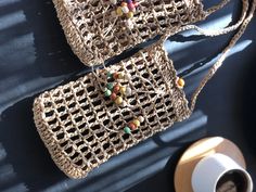 two purses sitting on top of a table next to a cup