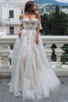 a woman in a wedding dress standing on a balcony with her hand on her hip