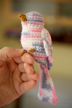 a small knitted bird sitting on top of a persons hand