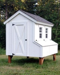 a small white outhouse in the grass