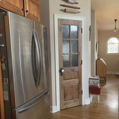 a stainless steel refrigerator and wooden cabinets in a kitchen with hardwood floors, white walls and wood flooring