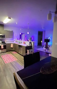 a large kitchen with purple lighting in the ceiling and wooden flooring on the walls