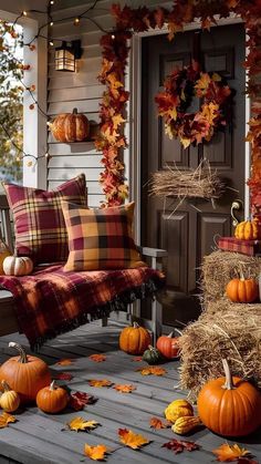 a porch decorated for fall with pumpkins and hay bales