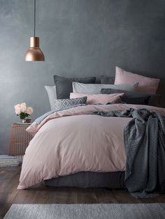 a bedroom with grey walls and pink bedding