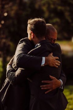 two men in suits hugging each other outside