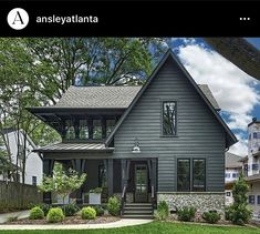 a gray house with lots of windows and landscaping