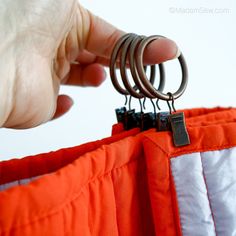 a person is trying to open an orange jacket with metal rings on it and there are other items in the pocket