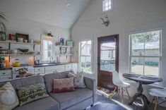 a living room filled with furniture next to a kitchen and dining room table in front of a window