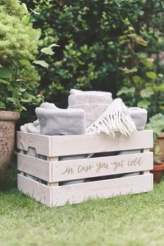 a wooden crate filled with towels sitting on top of a lush green field next to a potted plant