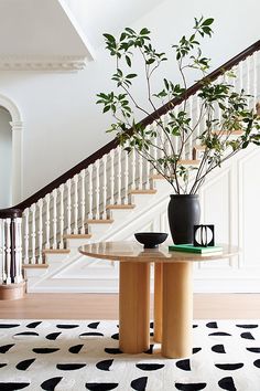 a table with a plant on it next to a stair case and coffee mugs