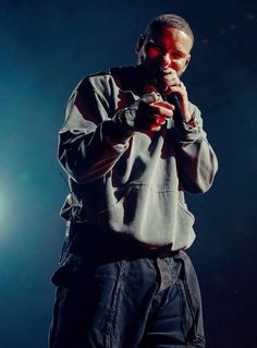 a man standing in front of a microphone on stage with his hand to his mouth