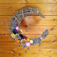 a wreath made out of twigs and flowers on a wooden floor with the letter o