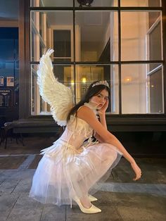 a woman dressed as an angel poses in front of a building