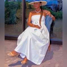 a woman in a white dress and hat sitting on a blue chair