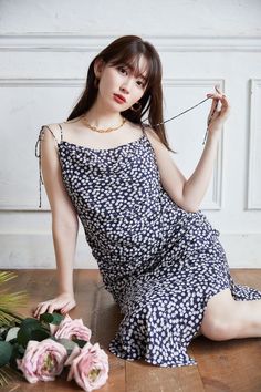 a woman sitting on the floor with flowers in front of her and wearing a dress