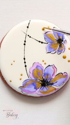 a white plate with purple flowers painted on it and a pair of scissors next to it