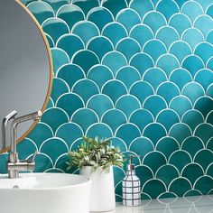 a white sink sitting under a bathroom mirror next to a blue tiled backsplash