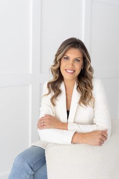 a woman sitting on top of a white couch with her arms crossed and smiling at the camera