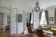 a living room filled with furniture and a chandelier hanging from the side of it