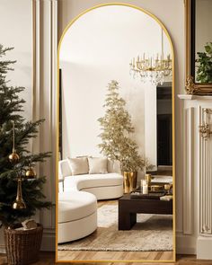 a living room filled with furniture and a christmas tree in front of a large mirror