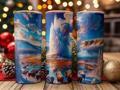 three travel mugs sitting on top of a table next to a christmas tree and decorations