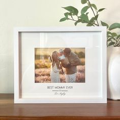 a couple kissing in front of a white vase with green leaves on it and the words best mom ever