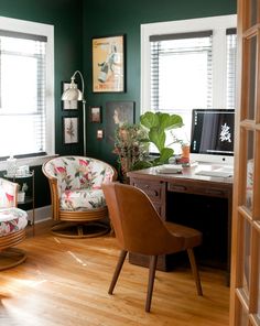 a chair and desk in a room with green walls, wood floors and wooden shutters