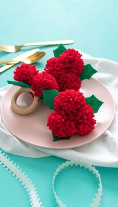 two red pom - poms sitting on top of a plate next to scissors