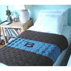 a bed with a blanket on top of it next to a night stand and bookshelf