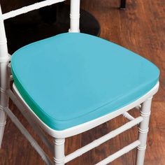 two white chairs with blue cushions sit on wooden floors in front of a black table