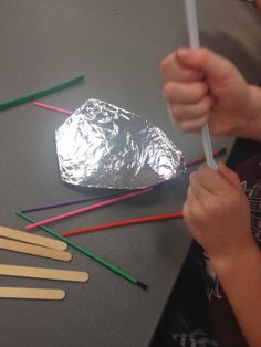 a child is making popsicles with aluminum foil and colored straws on the table