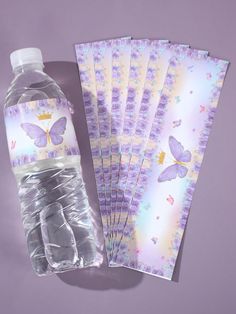 the water bottle is next to several folded paper cards with butterfly designs on them,